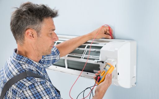 Portrait Of A Mid-adult Male Technician Testing Air Conditioner With Digital Multimeter